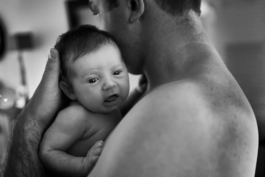 père tient son nouveau né contre son torse - photographe de famille à Amiens